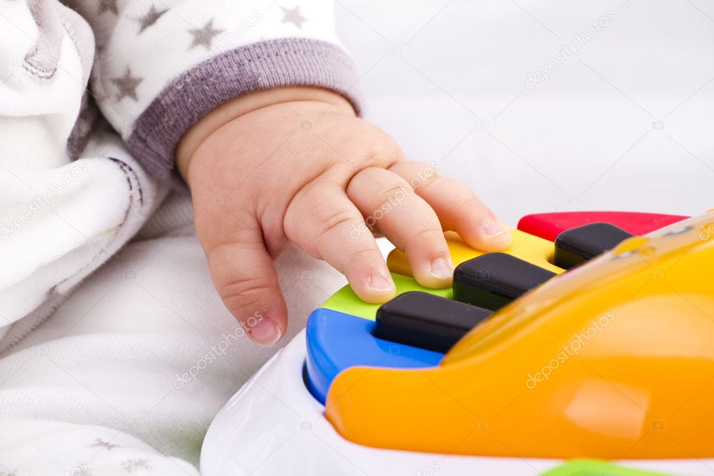 Little baby hand pianist plays on a colorful toy piano