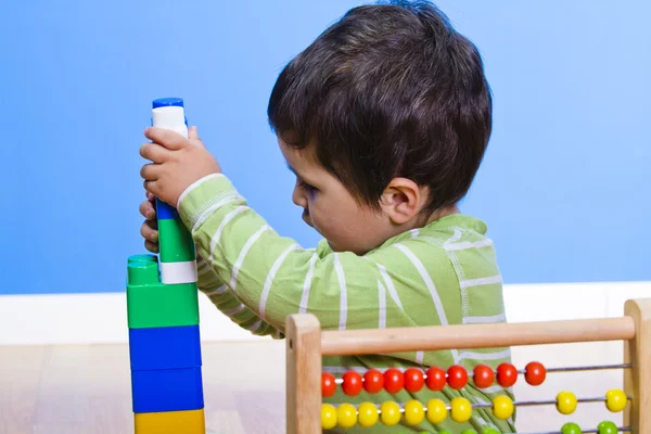 Ребенок играет с развивающими игрушками на деревянном фоне — стоковое фото