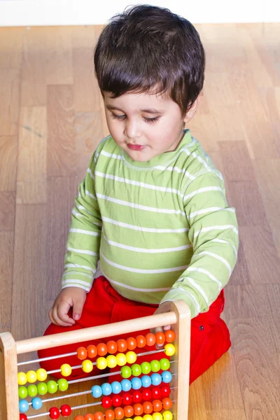 Кавказский ребенок в зеленой рубашке играет с ярким красочным блоком — стоковое фото