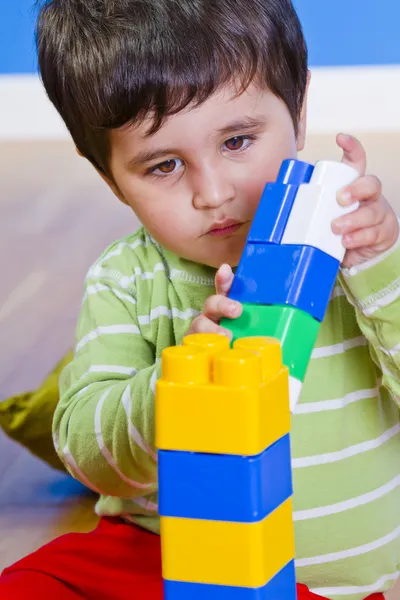 Европейский мальчик играет с пластиковыми красочными блоками — стоковое фото