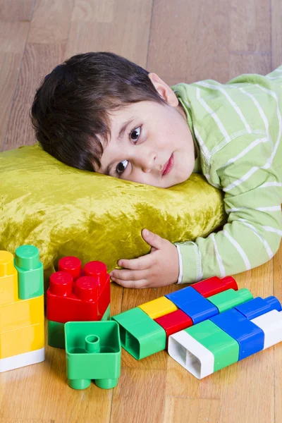 Sevimli küçük esmer çocuk oyuncakları ile otururken oynuyor — Stok fotoğraf