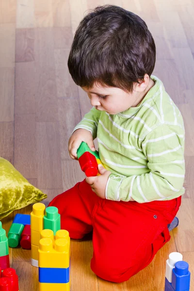 Szczęśliwy mały chłopiec jest budowa wieży bloku kolorowe zabawki — Zdjęcie stockowe