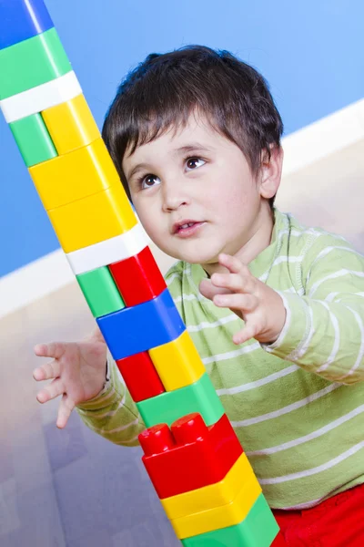 Смешной маленький мальчик играет с пластиковыми красочными блоками, студия ш — стоковое фото