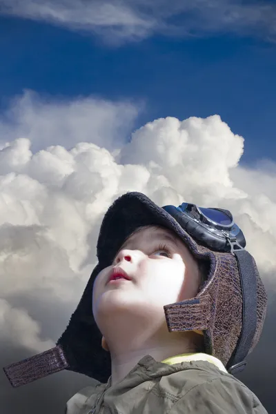 Ett barn klädda i piloten tittar in i den blå himlen — Stockfoto
