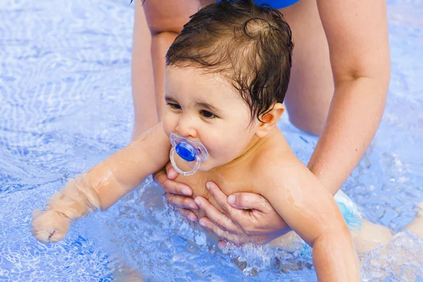 stock image Newborn baby with a pacifier playing in the pool with his mother