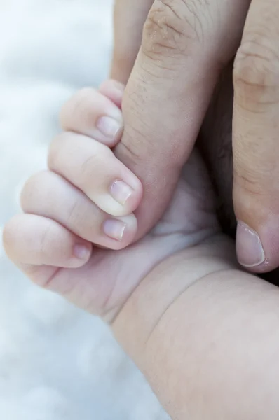 Mano de bebé agarrando el dedo del pie de su padre —  Fotos de Stock