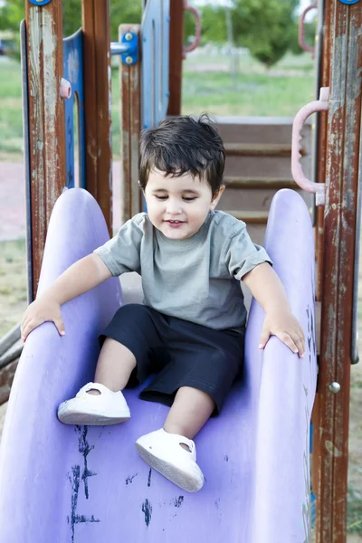 Cute baby playing on sliding board, smiling — Stock Photo, Image