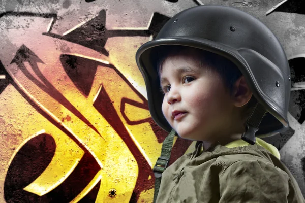 Baby spelen oorlog met militaire helm tegen graffiti pagina — Stockfoto