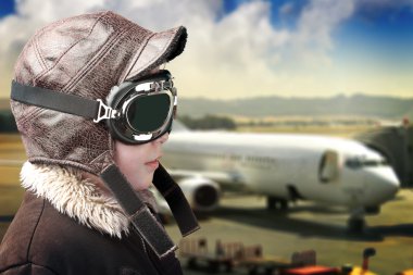 Boy playing with pilot hat and airport background clipart