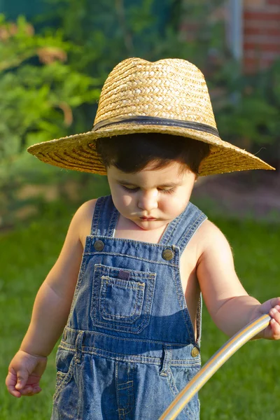 Mały ogrodnik chłopiec dziecko podlewanie trawy w poważny sposób — Zdjęcie stockowe