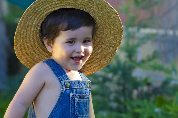 Маленький мальчик садовник улыбается игриво — стоковое фото