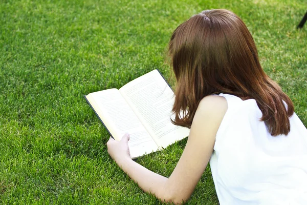 Ung smuk pige læser en bog udendørs - Stock-foto