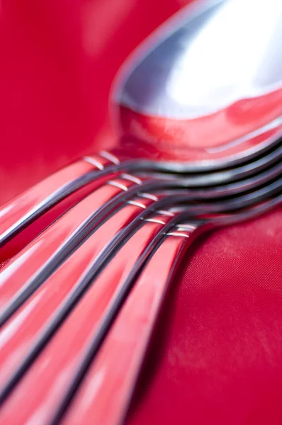 Spoons on a decadent red silk tablecloth — Stock Photo, Image