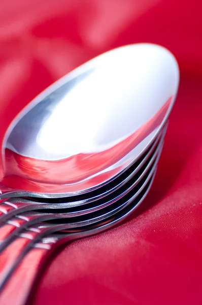Spoons on a decadent red silk tablecloth — Stock Photo, Image