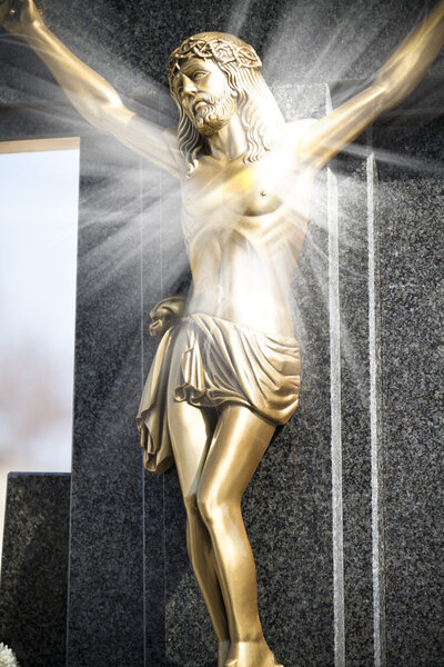 Иисус Христос на каменном кресте с мистическими лучами света
