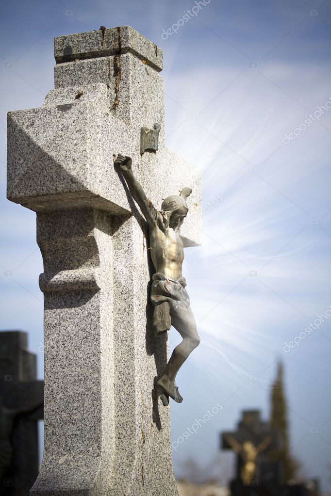 Jesus Christ on stone cross, cemetery scene with mystic rays of