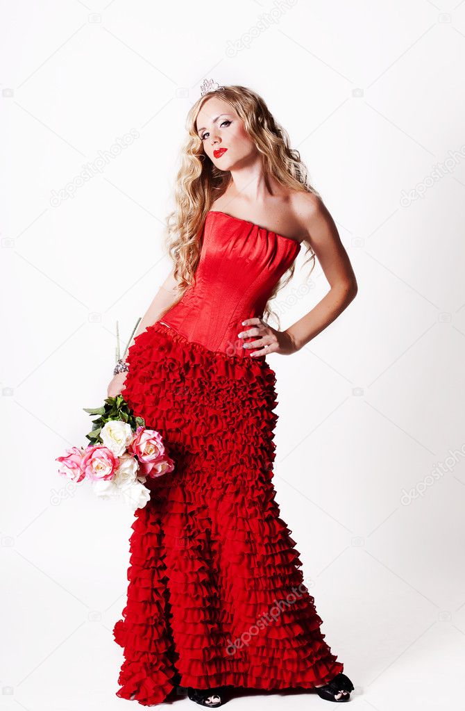 The beautiful girl in a long red dress holds an exotic flower in a hand ...