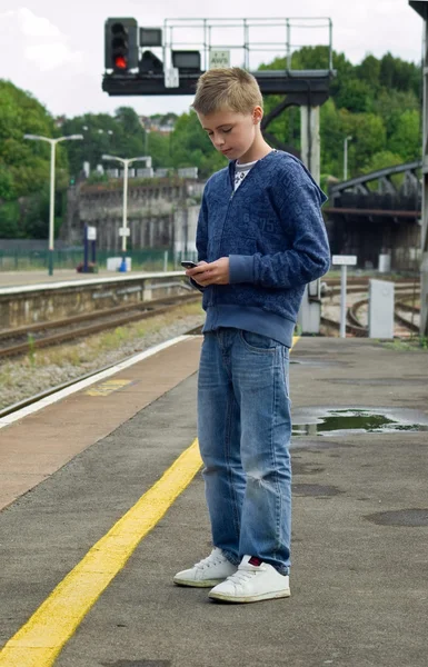 Youth texting at railway station — Stock Photo, Image