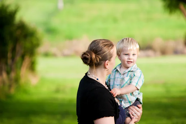 Een moeder buiten met haar kleine jongen in een veld buiten gree — Stockfoto