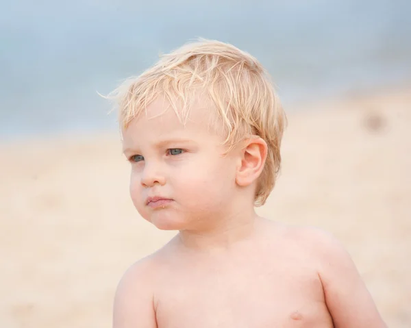 Un pequeño pelo rubio, de ojos azules, niño de un año en la playa. . — Foto de Stock