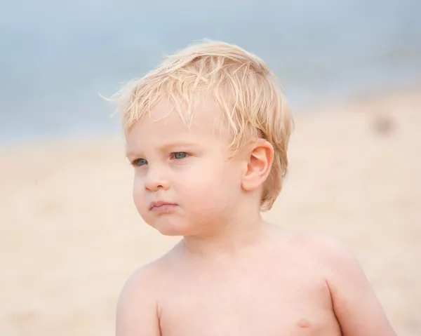 Trochę blond włosy, niebieskie oczach jeden-letni chłopak na plaży. — Zdjęcie stockowe