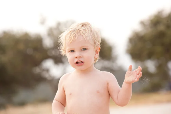 Lite blont hår, blå ögon ett år gammal pojke på stranden. — Stockfoto