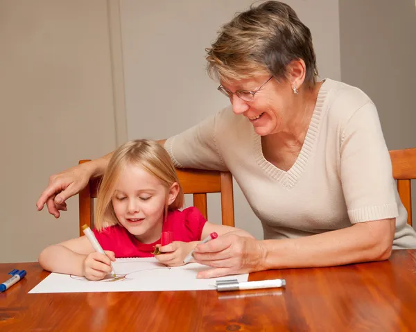 Een klein meisje tekenen met haar verzorger — Stockfoto