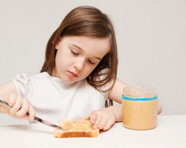 A young girl makes a peanut butter sandwich clipart