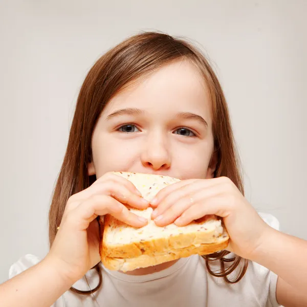 Una giovane ragazza mangia una sabbia fatta di pane integrale — Foto Stock