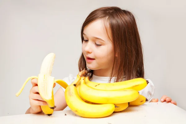 A young girl eats a banana — Zdjęcie stockowe