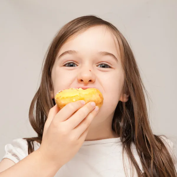 Una joven se come un donut —  Fotos de Stock
