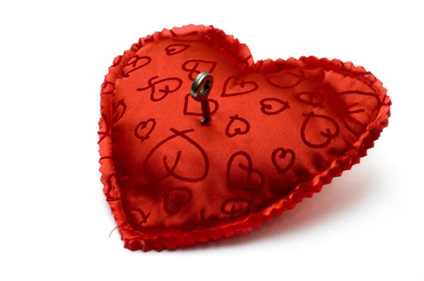 Small key opening a red heart shaped pillow — Stock Photo, Image