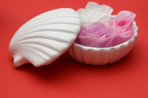 Clay shell holder of soap roses on red background — Stock Photo, Image