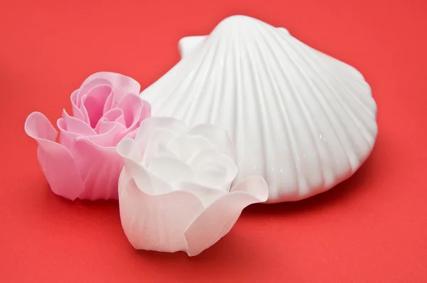 Clay shell with soap roses decoration on red background — Stock Photo, Image