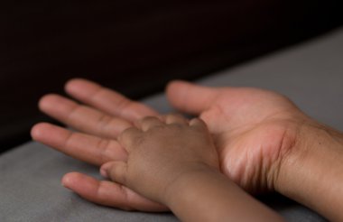 Hand of a baby in his mother's hand clipart