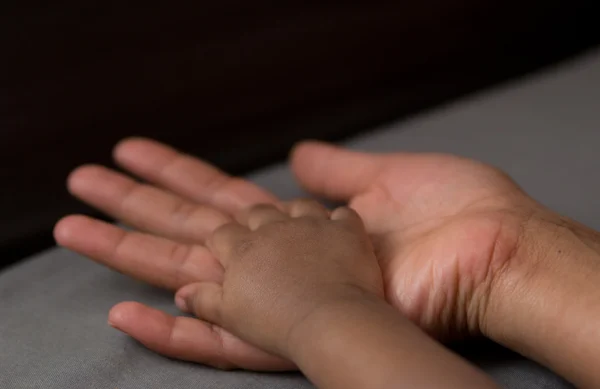 La main d'un bébé dans la main de sa mère — Photo