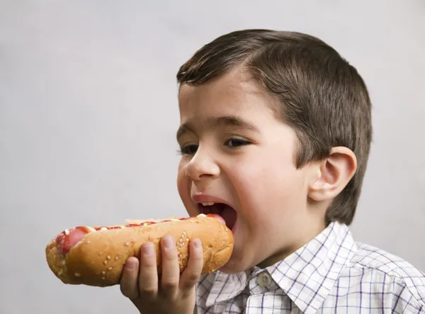 Fiú eszik hotdog Stock Kép