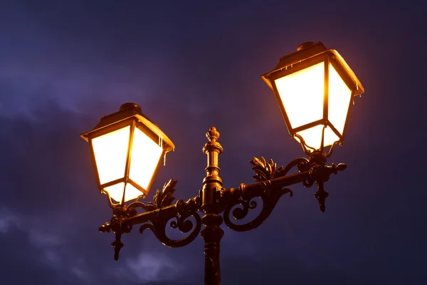 Lampada da strada splendente di notte contro il cielo nuvoloso drammatico — Foto Stock