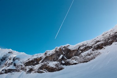 Airplane Trail in Blue Sky above Mountain Peak, French Alps clipart