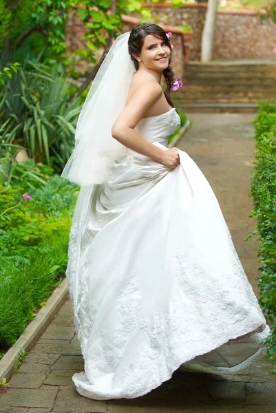 Όμορφη νύφη σε ένα λευκό φόρεμα με τα πόδια από το πάρκο — Φωτογραφία Αρχείου