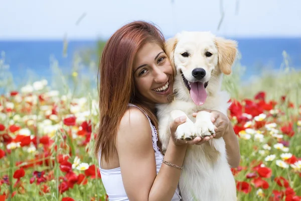 Jovem feliz brincando com seu cachorro em um prado — Fotografia de Stock