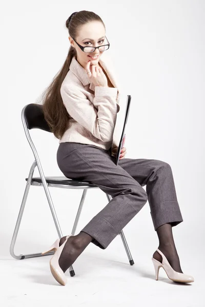 Piękna młoda kobieta w garniturze siedzi i uśmiechając się — Zdjęcie stockowe