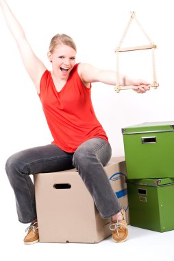 Young woman with a house symbol sits on moving box clipart