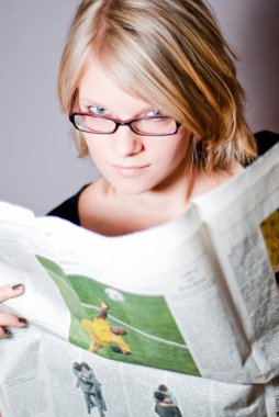 Young woman with glasses reading newspaper V1 clipart