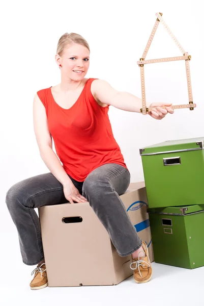 stock image Young woman with a house symbol sits on moving box