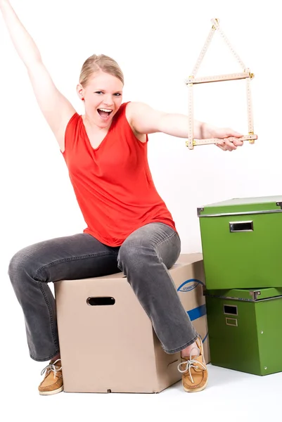 stock image Young woman with a house symbol sits on moving box