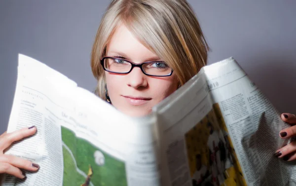 Stock image Young woman with glasses reading newspaper V2