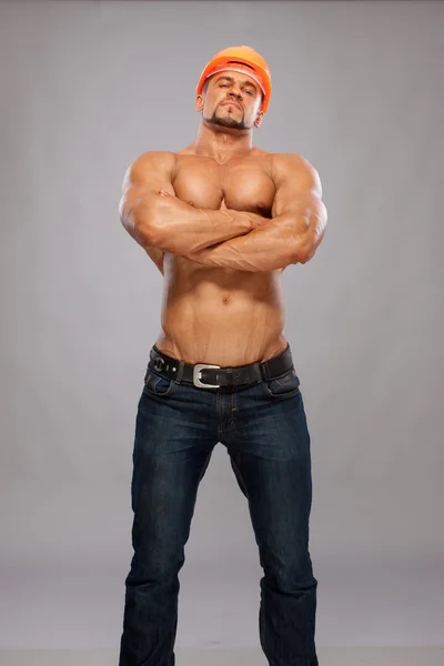 Construtor masculino muscular em fundo cinza — Fotografia de Stock