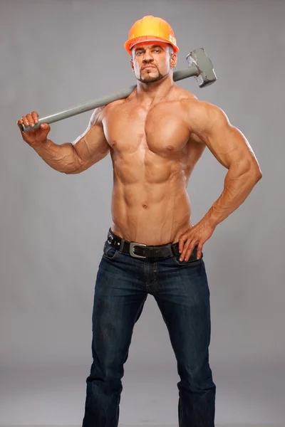 Jeune et beau constructeur avec un marteau et un corps sexy — Photo