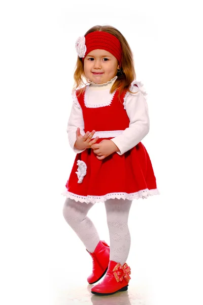 En liten flicka i en stickad klänning på en vit bakgrund — Stockfoto
